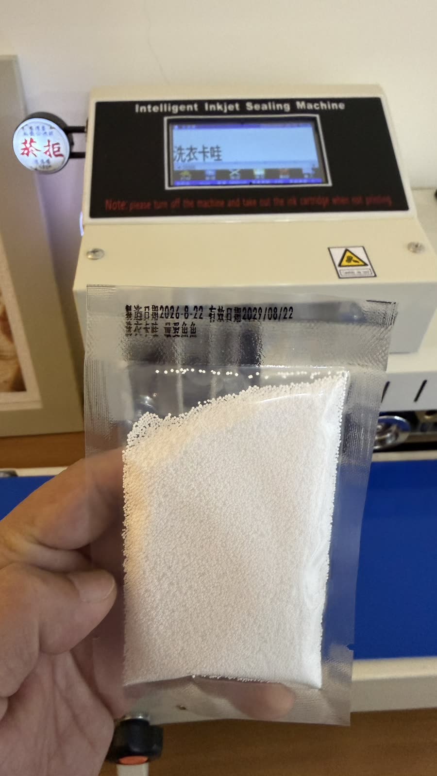 手持分裝完成的粉狀小包裝，印有製造與有效日期